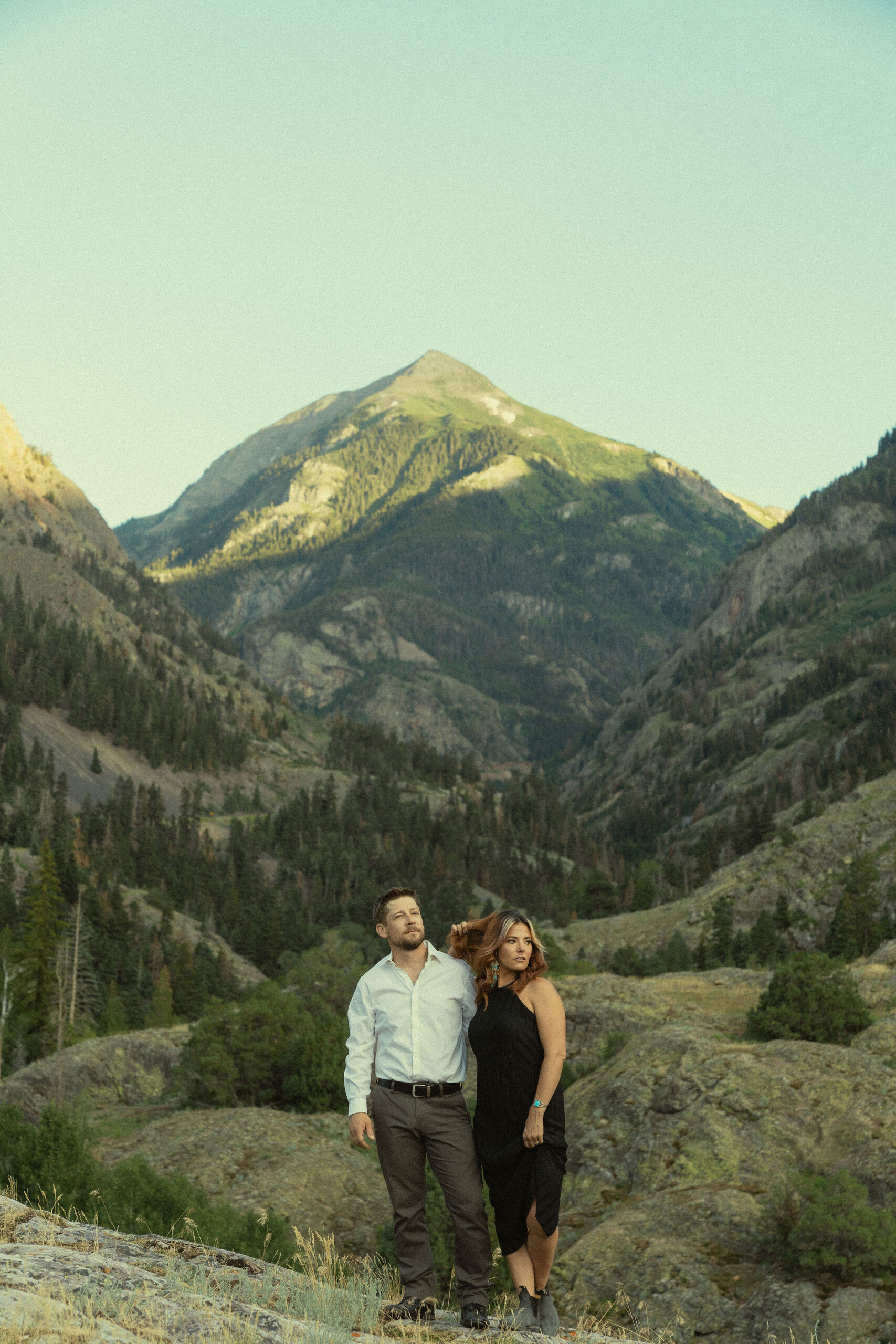 beautiful couple pose during their Ouray engagement photos with the Rocky mountains outside Ouray, Colorado