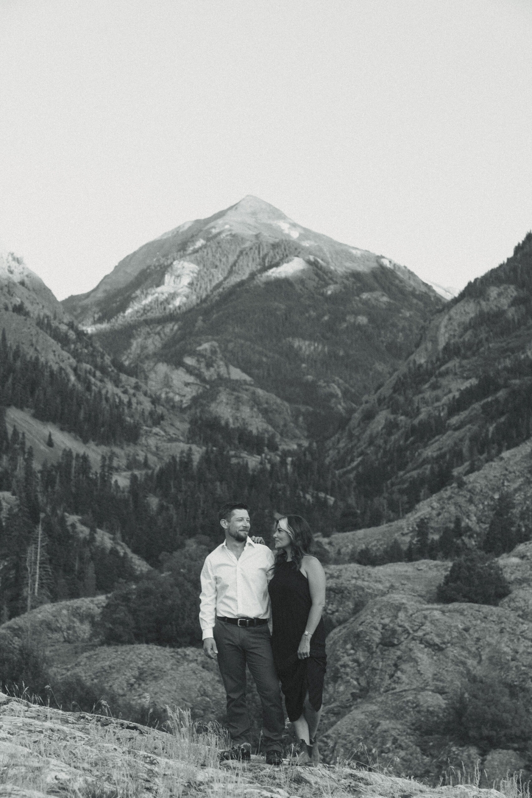 beautiful couple pose during their Ouray engagement photos with the Rocky mountains outside Ouray, Colorado