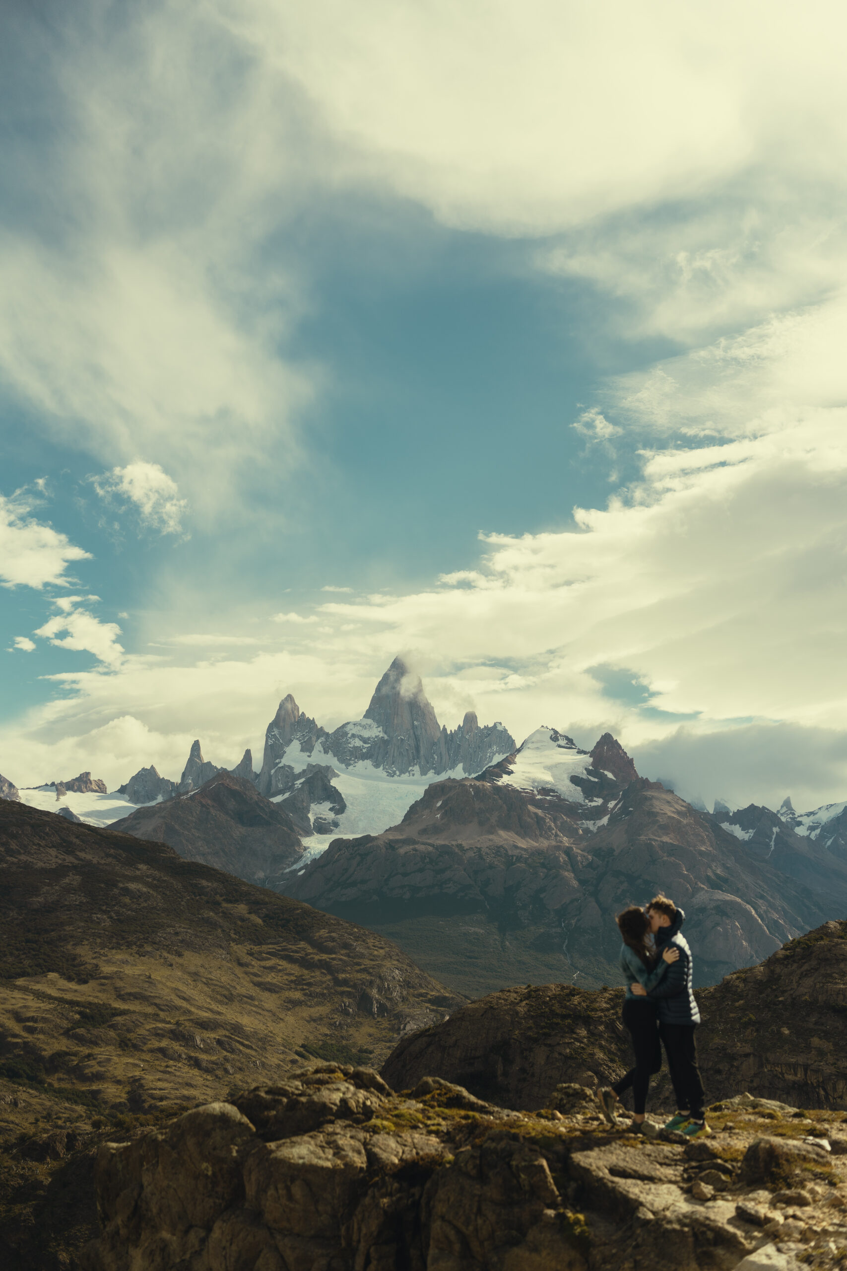 couple share a kiss in front of fitzroy as the clouds caress the peak one of the worlds best elopement destinations