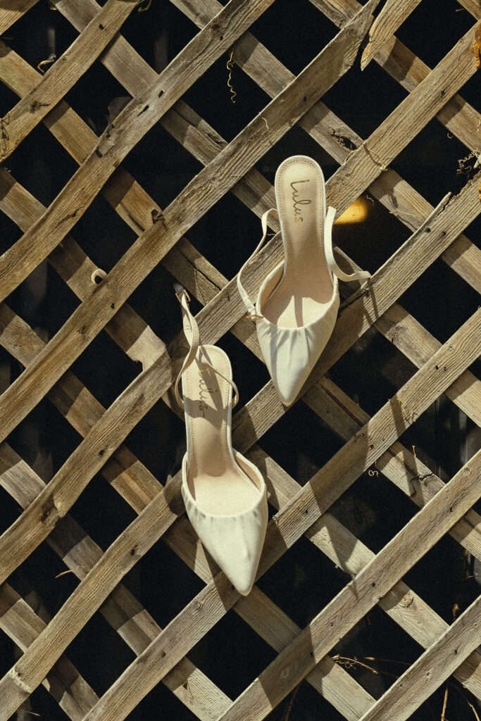 brides shoes hang in a wooden fence as she prepares for her stunning wedding day