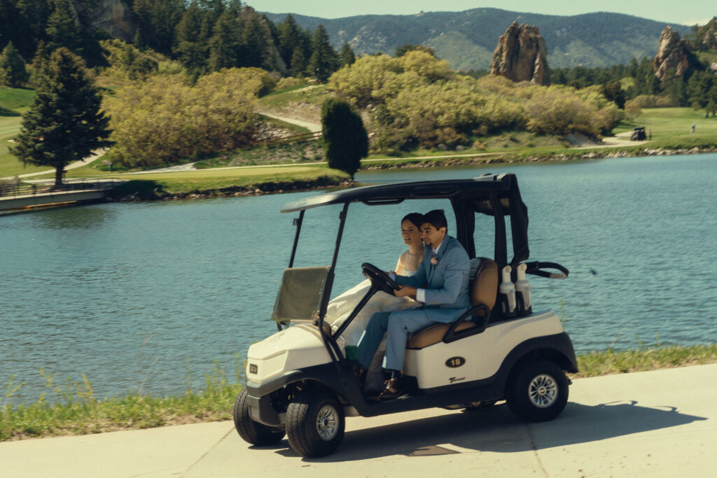 bride and groom ride the golf cart beside the romantic lake