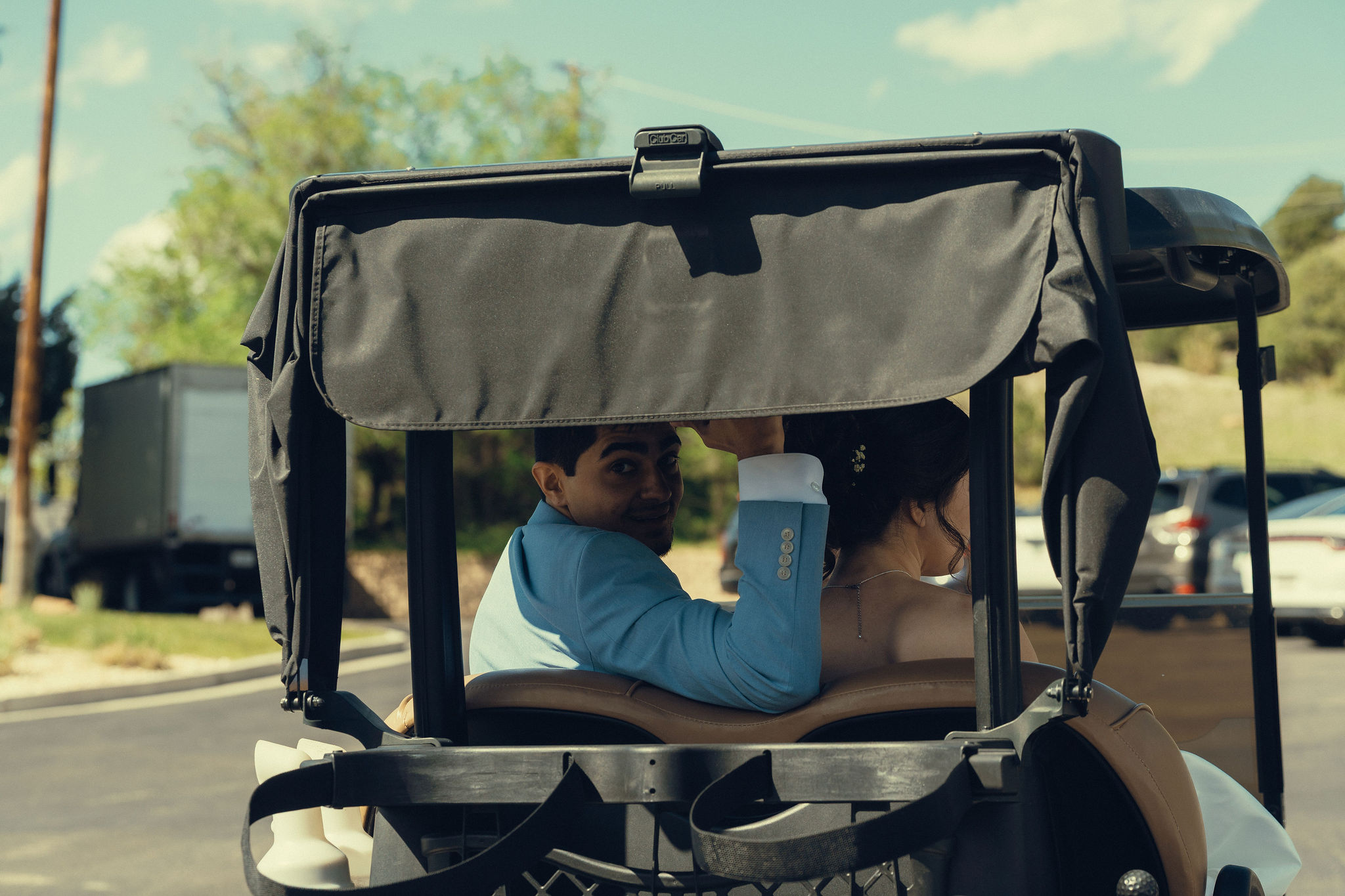 bride and groom ride in the golf cart together during their country club wedding day