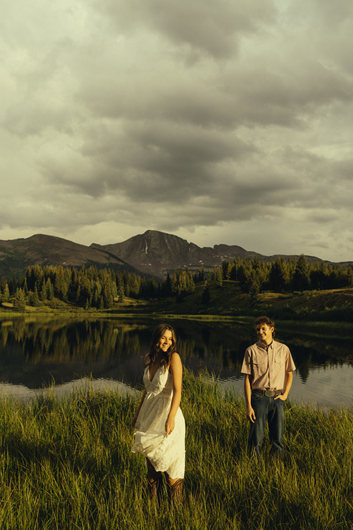 beautiful couple pose by the lake during their Colorado mountain engagement photoshoot