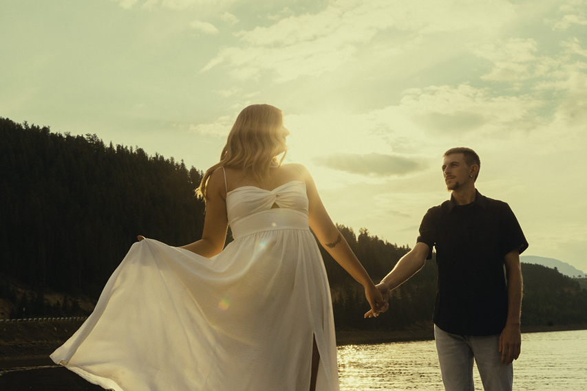 beautiful couple hold hands by the waters edge