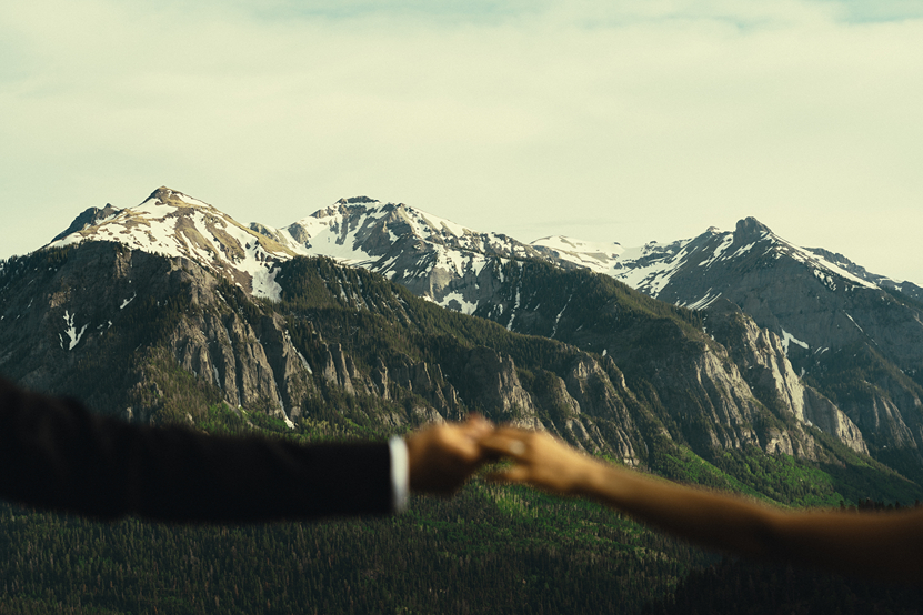 couple hold hands with the San Juans snowy peaks in the background