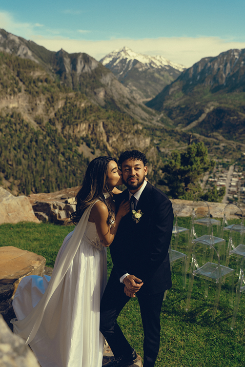 bride and groom share a kiss at the edge of their ceremony site