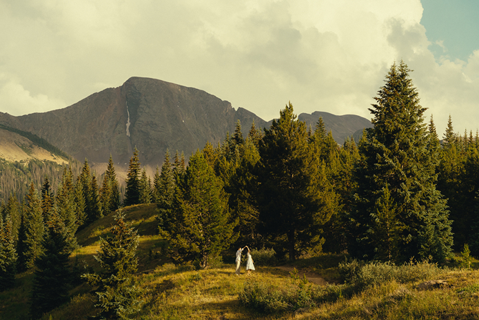 bride and groom dance with the mountains in the background