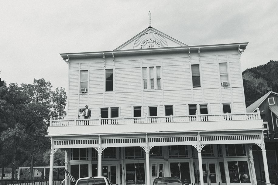 beautiful bride and groom stand on the western hotel balcony after their Colorado wedding day