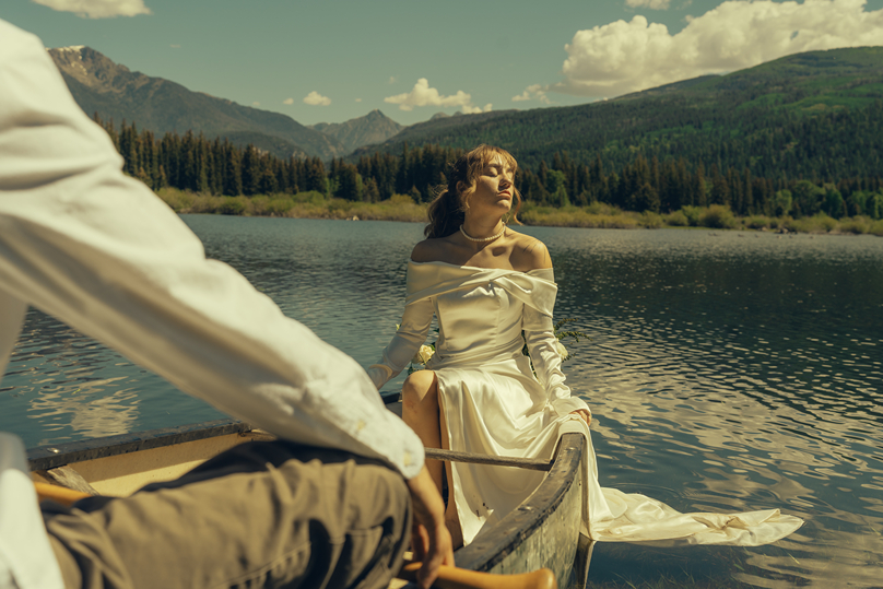 bride basks in the sunlight on the edge of the canoe as she enjoys her durango colorado wedding day