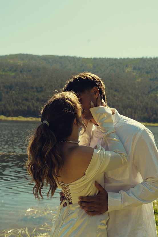 bride and groom share a kiss by the lakeside
