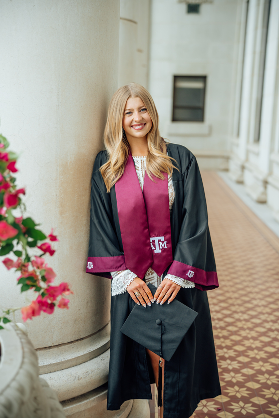 senior blonde girl poses in her Texas A&M robe during her texas a&m graduation photos