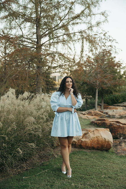 girl in blue dress poses in the nature on campus during her texas a&m graduation photos