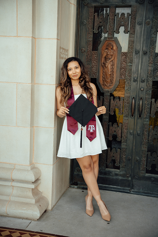 senior poses with her cap and gown during her on campus photoshoot