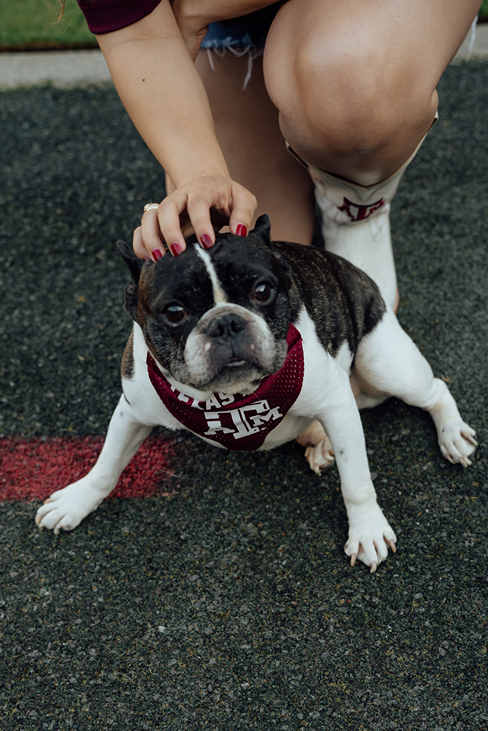 girl poses in her 12th man jersey in Kyle Field with her dog during her texas a&m graduation photos