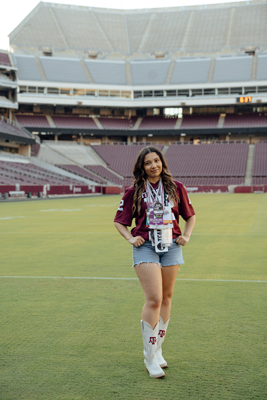 girl poses in her 12th man jersey in Kyle Field during her texas a&m graduation photos
