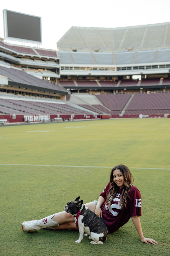 girl poses in her 12th man jersey in Kyle Field with her dog during her texas a&m graduation photos
