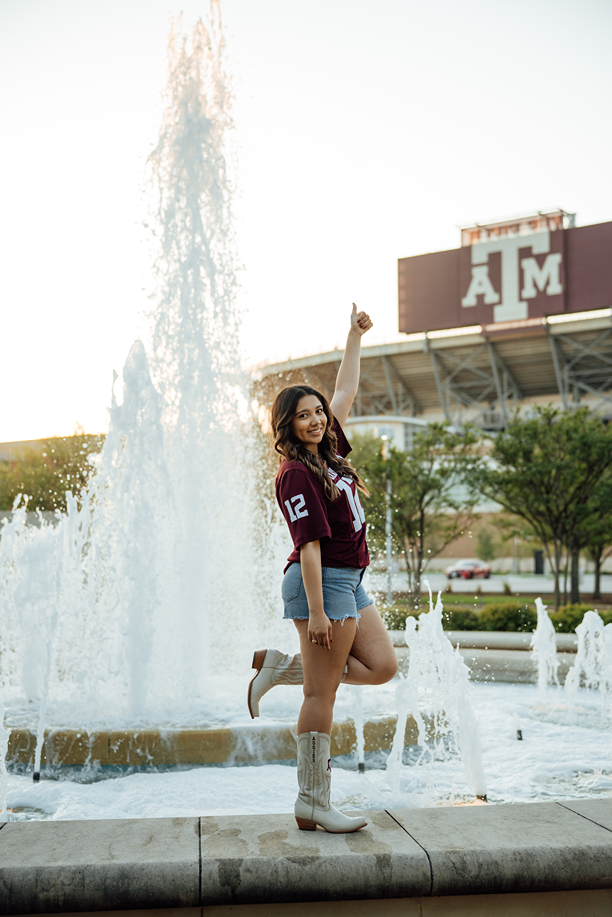 girl poses in her 12th man jersey in Kyle Field during her texas a&m graduation photos