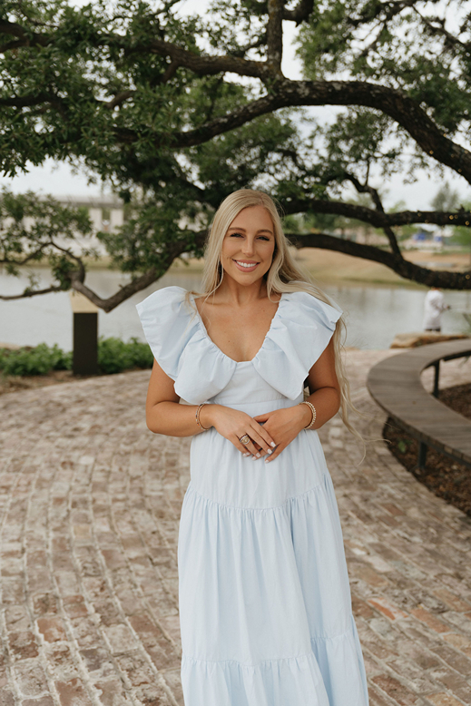 girl in blue dress poses in the nature on campus during her senior session