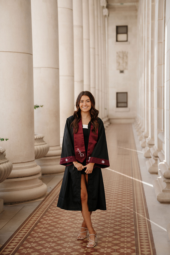 senior burnette girl poses in her Texas A&M robe during her on campus graduation photos