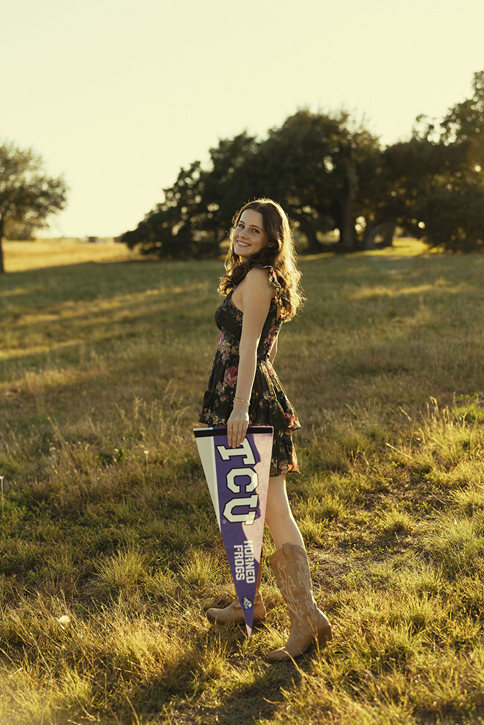 TCU grad walks through a field during her senior sesion