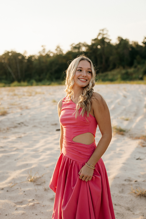senior poses on the beach during her senior photo session with Sasha