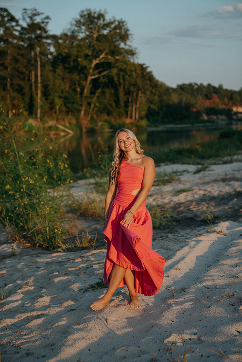 senior poses on the beach during her senior photo session with Sasha