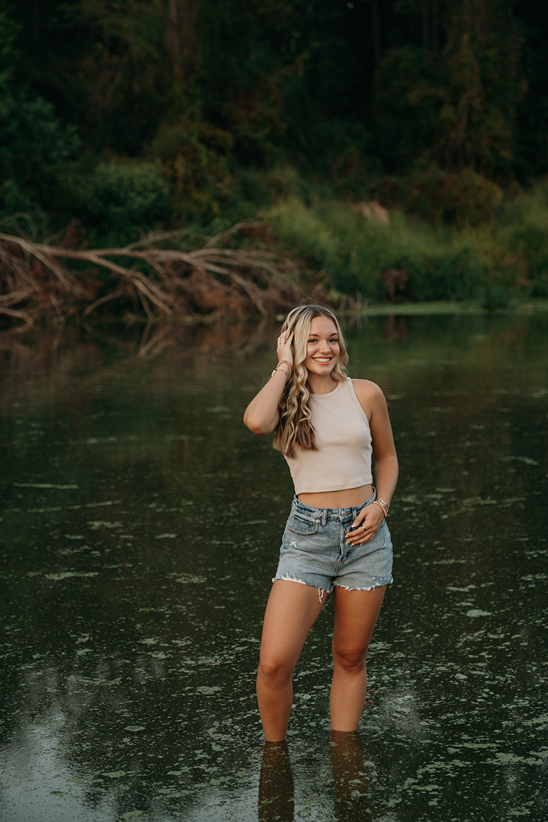 senior stands in a creek during her senior photoshoot a unique idea!