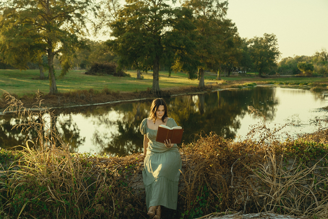 senior reads a book during her photoshoot with Sasha