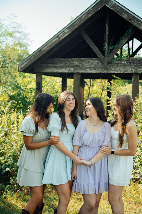 girl group hold each other and share a laugh during their outdoor college station senior photo session