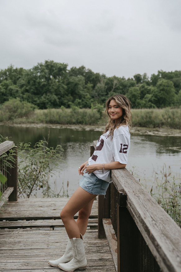 girl poses against the handrail with the Texas pond behind her
