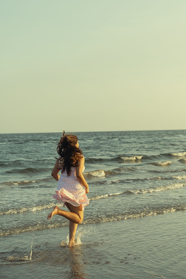 Texas senior runs on the beach as the waves splash her ankles